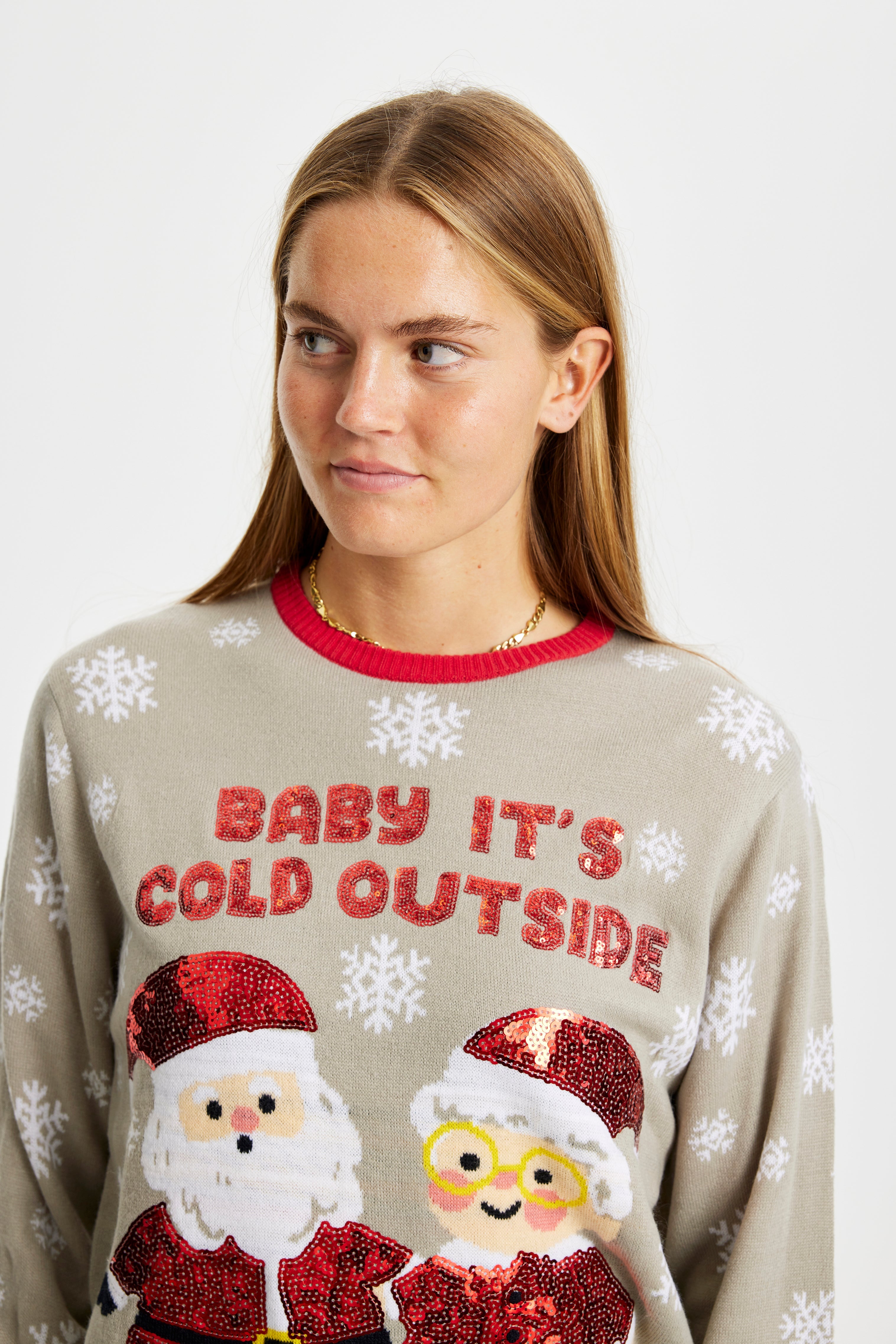 En dame iført en julesweater med snefnug og en glitrende julemand og -dame.